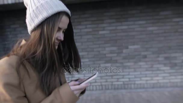 Ung kvinna skriver sms på smartphone medan promenad i city — Stockvideo