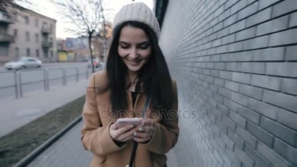 街で散歩しながらスマート フォンの sms を書く若い女性 — ストック動画