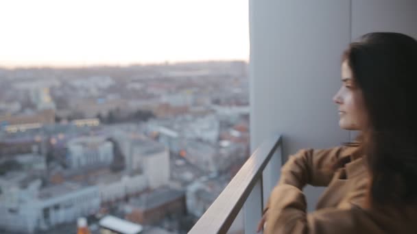 Молодая женщина ищет городской пейзаж с высокого небоскреба — стоковое видео