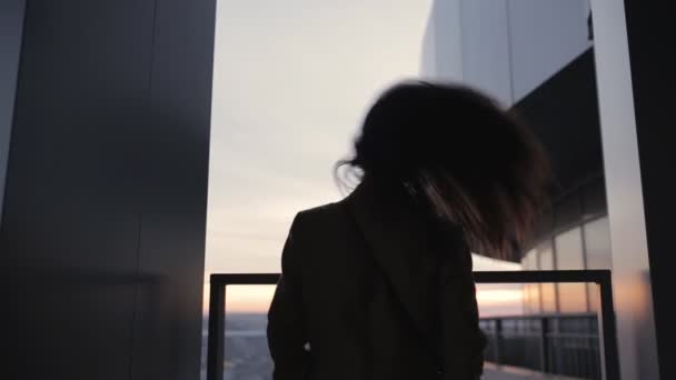 Silhouette einer Frau auf hohem Wolkenkratzer wirft Haare — Stockvideo