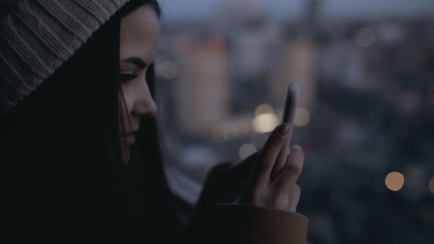 Femme photographiant le paysage urbain du soir depuis un gratte-ciel élevé. Lumières de ville . — Video