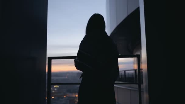 Silhouette of woman on high skyscraper dress her scarf — Stock Video