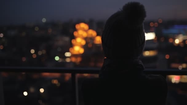 Mujer mirando al paisaje de la ciudad de la noche desde el rascacielos alto. Ciudad luces de noche . — Vídeos de Stock