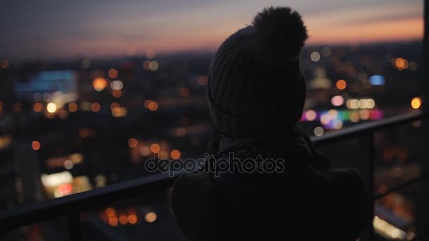 Mujer fotografiando paisaje de la noche desde un rascacielos alto. Ciudad luces de noche . — Vídeos de Stock