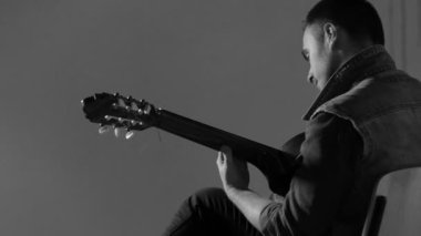 Akustik gitar gri duvar arka plan - tek renkli oturan oynayan adam gitarist