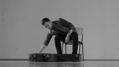 Gitarist bir gitar durumda dışarı alır ve oynamak - tek renkli başlar