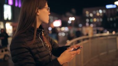 Akıllı telefon ekranına şehir gece görünümlü kullanan kadın