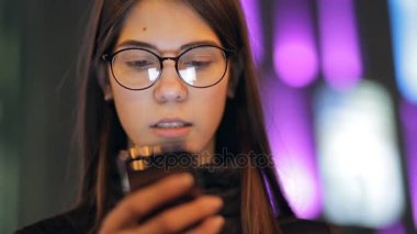 Gece ışıklı şehirde onun akıllı telefon dokunmatik ekran kullanan kadın