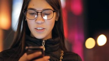 Görüntülü görüşme için gece ışıklı şehirde onun akıllı telefon kullanan kadın