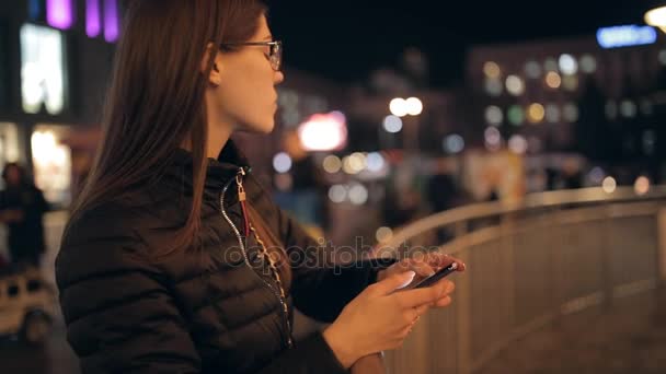 Γυναίκα χρησιμοποιώντας έξυπνο τηλέφωνο ψάχνει σε οθόνη στην πόλη νύχτα — Αρχείο Βίντεο