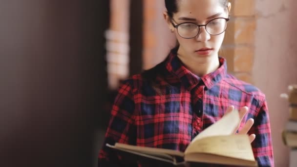 Aantrekkelijke vrouw in brillen lezen boek staande ter venster — Stockvideo