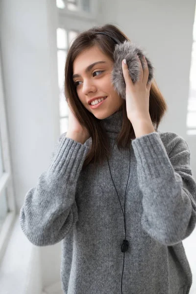 Chica adolescente con auriculares esponjosos escuchar música en la habitación blanca —  Fotos de Stock