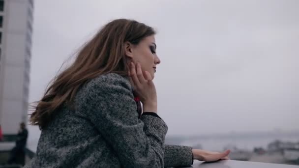 Mujer joven mirando al paisaje urbano desde el techo del edificio — Vídeos de Stock