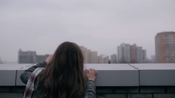 Young woman looking to cityscape from roof of building - back view — Stock Video