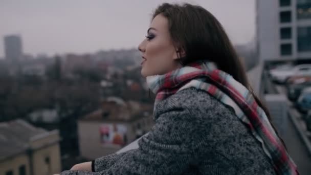 Mujer joven mirando al paisaje urbano desde el techo del edificio — Vídeo de stock