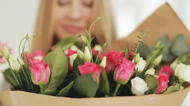 Женщина нюхает букет роз в студии — стоковое видео