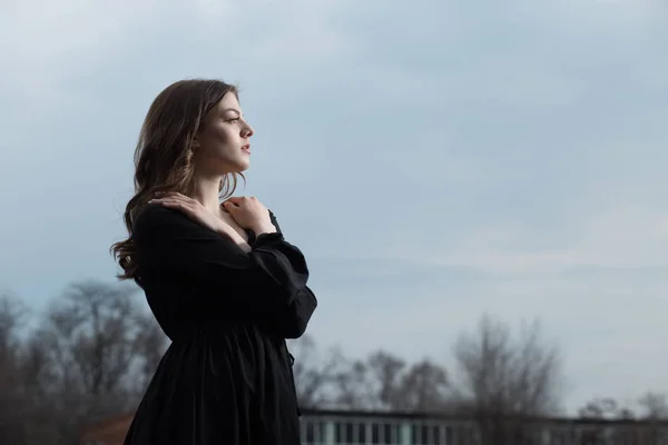 Bella donna in abito nero contro lo sfondo cielo sullen — Foto Stock