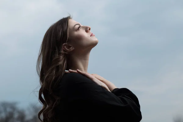 Mulher bonita em vestido preto contra fundo céu sullen — Fotografia de Stock