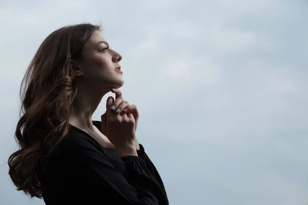 Mulher bonita em vestido preto contra fundo céu sullen — Fotografia de Stock