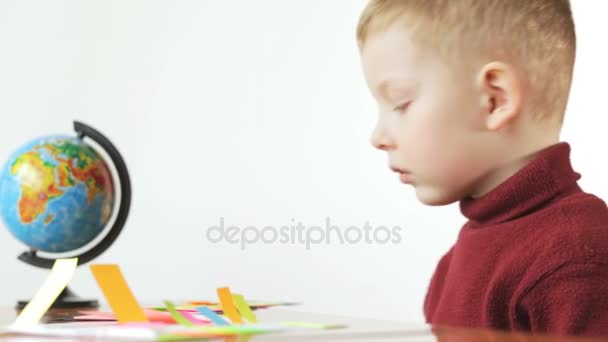 Kleine jongen lijm gekleurd papier op witte achtergrond. Voorschoolse educatie. — Stockvideo