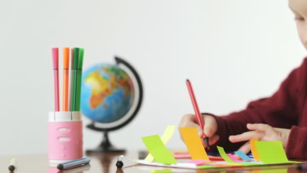 Little boy draws a markers on color paper, white background. — Stock Video