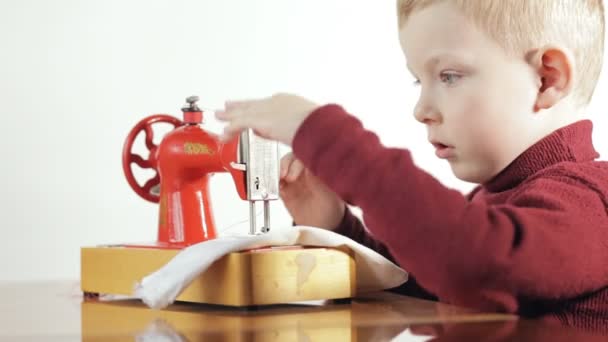 Niño pequeño coser la tela en la máquina de coser - fondo blanco — Vídeo de stock