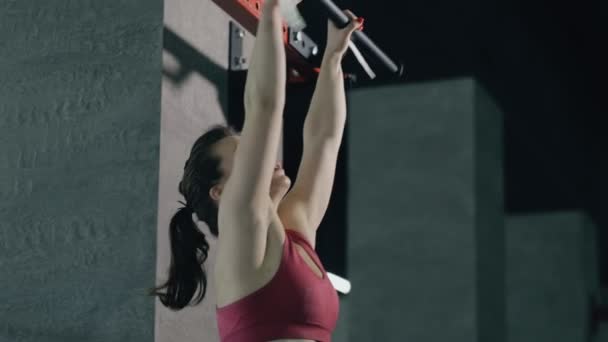 Сильна жінка накачує м'язи живота висить на горизонтальній планці — стокове відео