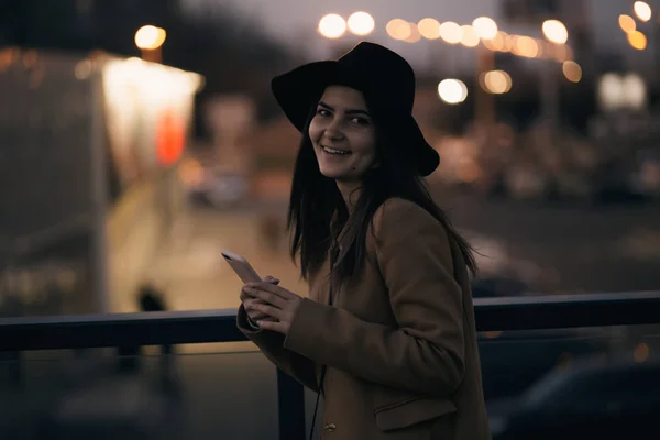 Kobieta w kapeluszu z telefonu komórkowego w nocy — Zdjęcie stockowe