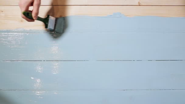 Man hand paints wooden board to blue color — Stock Video