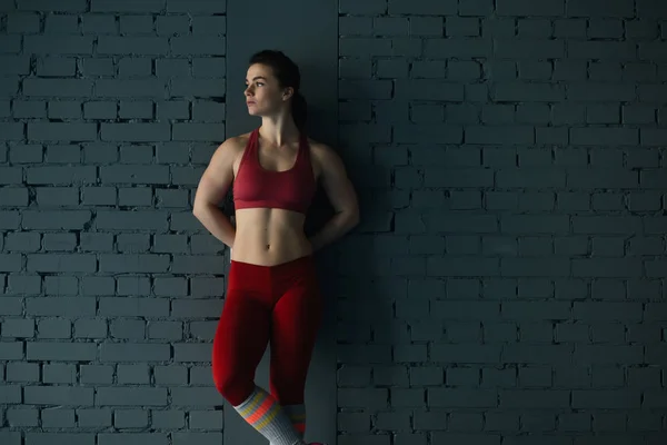 Sportskvinne i rødt ved murveggen – stockfoto