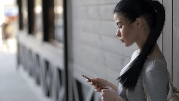 Femme contre un mur en bois appelant par smartphone en ville — Video