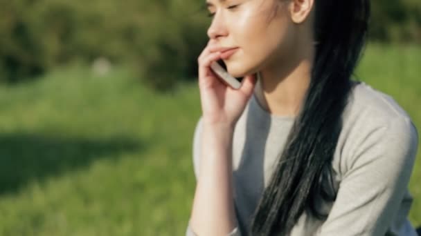 Femme parlant par téléphone intelligent assis sur l'herbe — Video