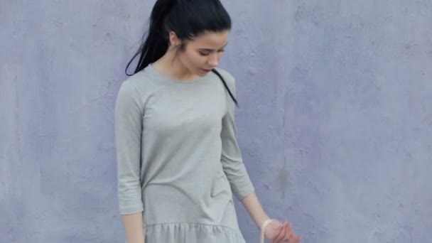Snygg kvinna mode poserar på violett vägg med väska — Stockvideo