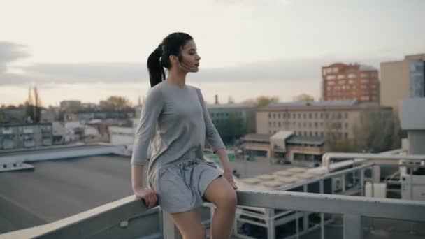 Стильная женщина сидит на крыше и расслабляется — стоковое видео