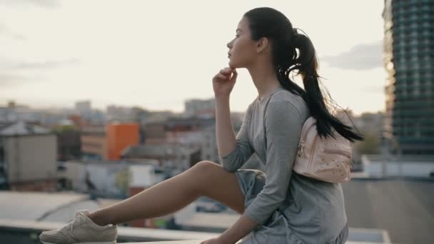 Стильная женщина сидит на крыше и позирует — стоковое видео
