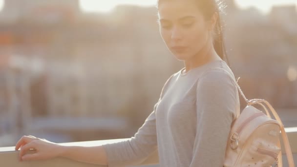 Jolie femme au coucher du soleil en ville regardant la caméra — Video