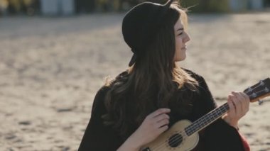 Ukulele plajda oynarken mutlu genç kadın