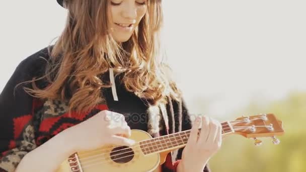 Щаслива молода жінка грає на укулеле на пляжі — стокове відео