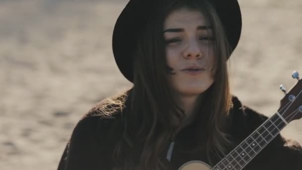Glad ung kvinna som spelar på ukulele på stranden — Stockvideo