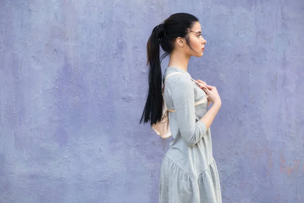 Mulher elegante com saco na parede violeta — Fotografia de Stock