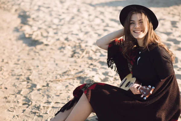 Onnellinen nuori nainen leikkii ukulele rannalla — kuvapankkivalokuva