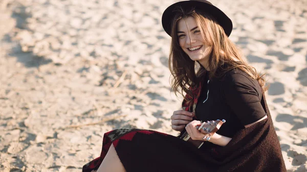 Счастливая молодая женщина играет на укулеле на пляже — стоковое фото