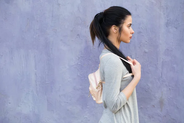 Stylische Frau mit Tasche an der violetten Wand — Stockfoto