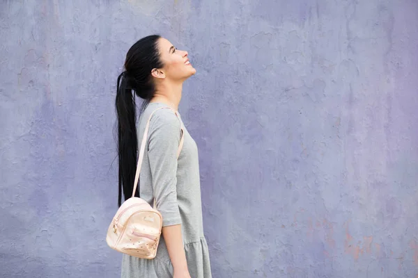 Mujer con estilo con bolsa en la pared violeta —  Fotos de Stock