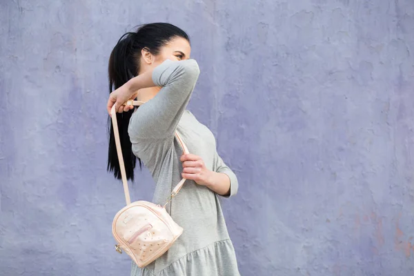 Mulher elegante com saco na parede violeta — Fotografia de Stock