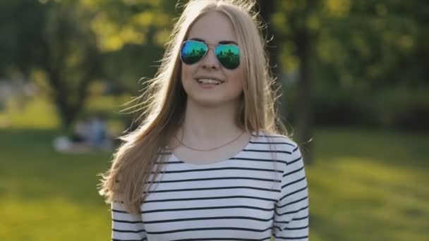 Dospívající dívka v sluneční brýle pózuje v parku — Stock video