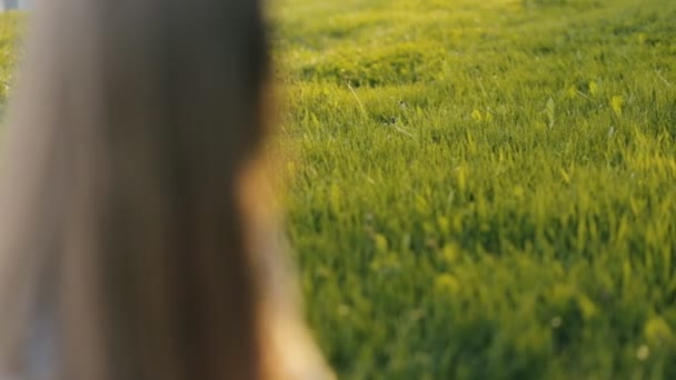 Tiener meisje zittend op gras en kijken naar de camera — Stockvideo