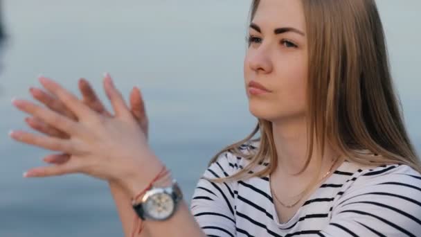 Adolescente chica mirando a la cámara sentado en el mar — Vídeos de Stock