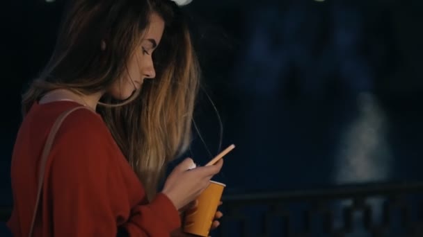 Jeune femme regardant vers le bas à son téléphone intelligent la nuit — Video