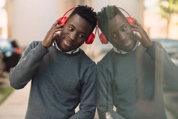 Hombre afroamericano con auriculares escucha música en la ciudad — Foto de Stock